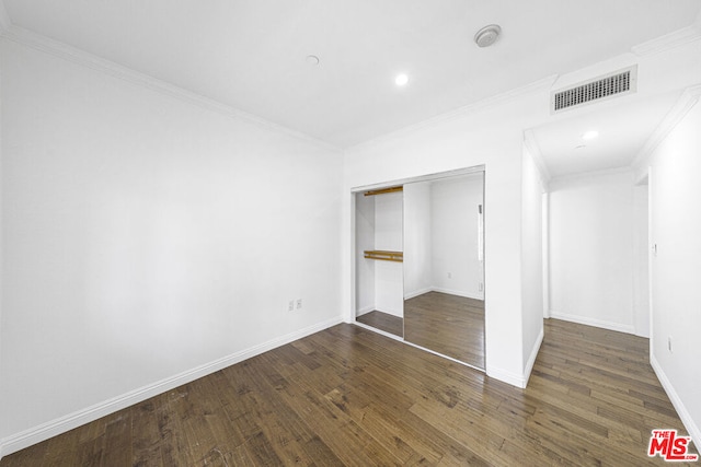 unfurnished bedroom featuring dark hardwood / wood-style flooring, crown molding, and a closet