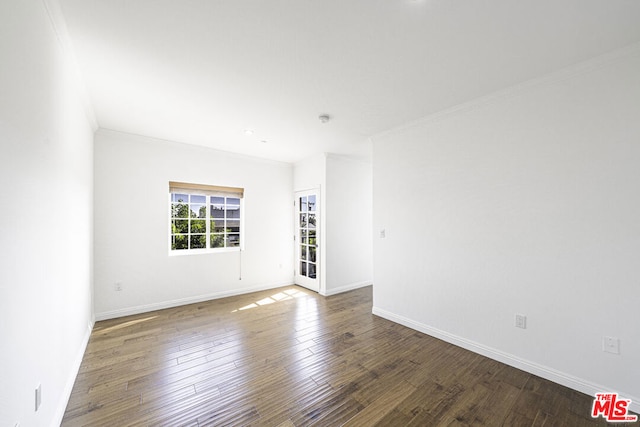 unfurnished room with ornamental molding and dark wood-type flooring