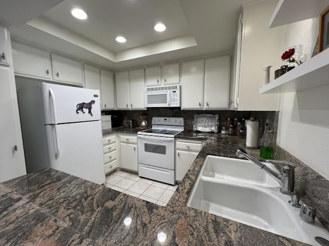 kitchen featuring sink, a raised ceiling, tasteful backsplash, kitchen peninsula, and white appliances