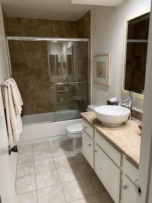 full bathroom featuring tile patterned floors, vanity, bath / shower combo with glass door, and toilet