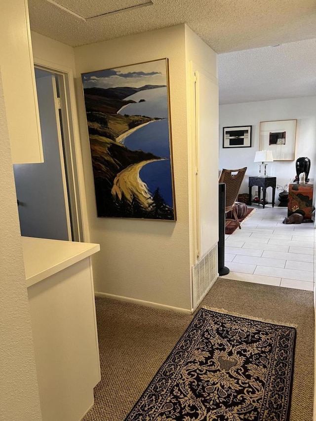 hallway with light colored carpet and a textured ceiling