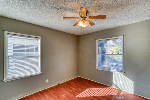 spare room with baseboards, a textured ceiling, a ceiling fan, and wood finished floors