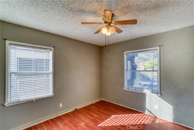 unfurnished room with baseboards, a ceiling fan, wood finished floors, and a textured ceiling