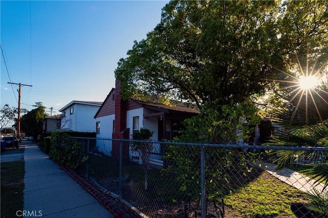 view of side of property featuring fence, a chimney, and stucco siding