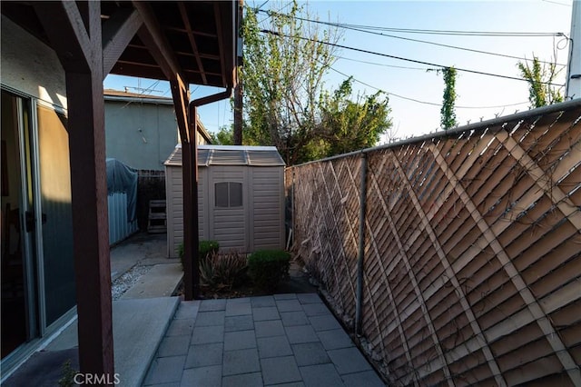 view of patio with an outbuilding, a storage unit, and a fenced backyard