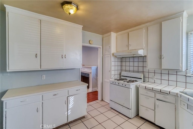 kitchen with gas range gas stove, light tile patterned flooring, white cabinetry, decorative backsplash, and under cabinet range hood