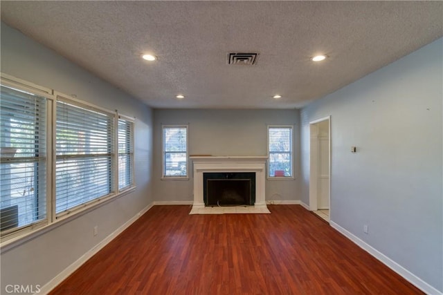 unfurnished living room featuring visible vents, baseboards, wood finished floors, and a fireplace with flush hearth