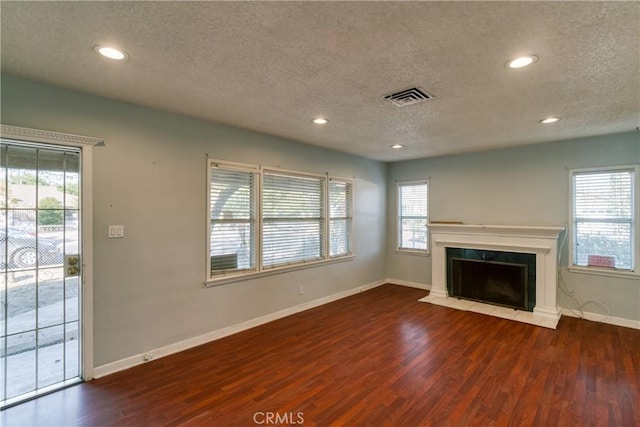 unfurnished living room featuring a textured ceiling, wood finished floors, and visible vents