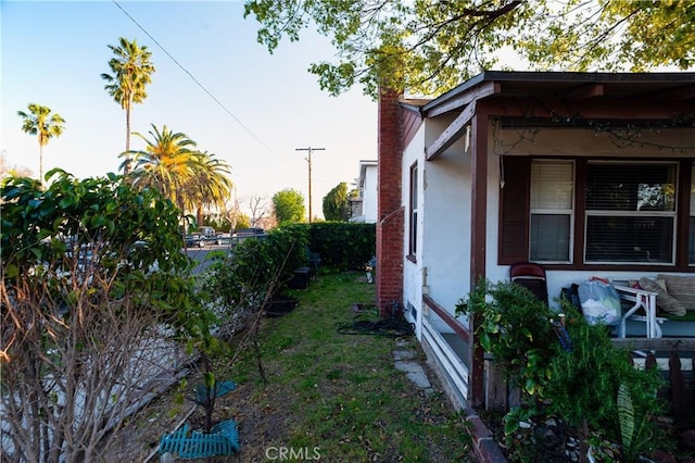 view of side of property featuring a chimney and stucco siding