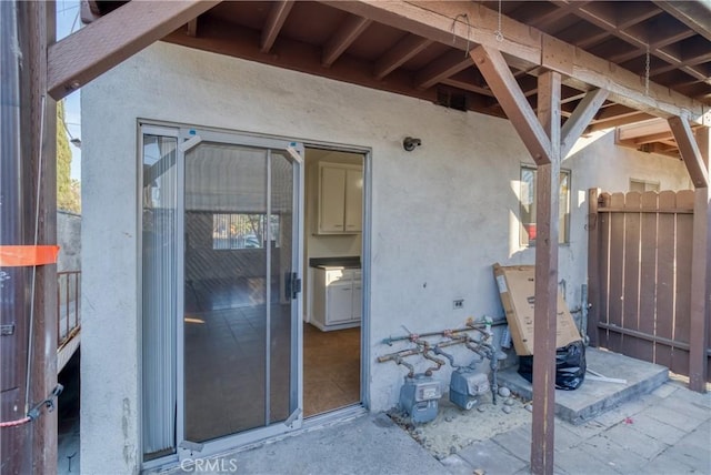 view of exterior entry featuring fence and stucco siding