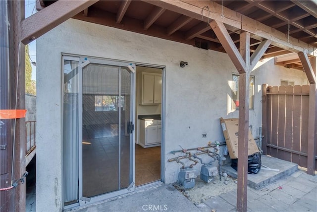 doorway to property featuring fence and stucco siding
