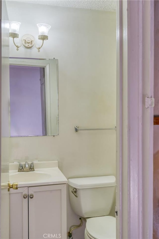 bathroom with toilet, vanity, and a textured ceiling