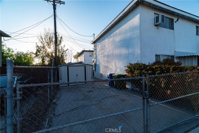 view of property exterior featuring an outdoor structure, fence, stucco siding, and a storage unit