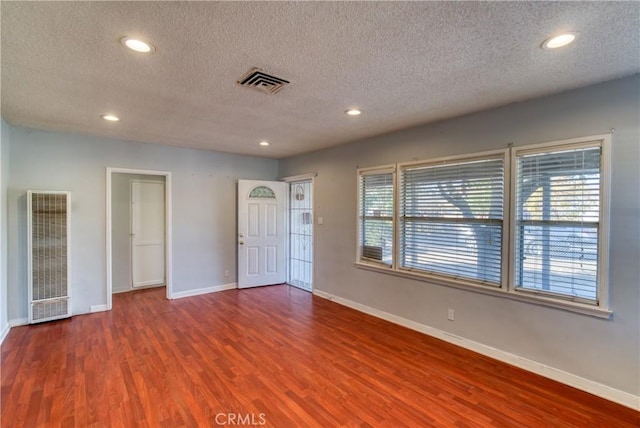 unfurnished room with a wealth of natural light, visible vents, and wood finished floors