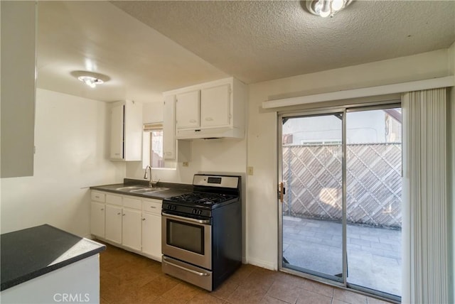 kitchen with a textured ceiling, white cabinets, gas stove, sink, and light tile patterned floors