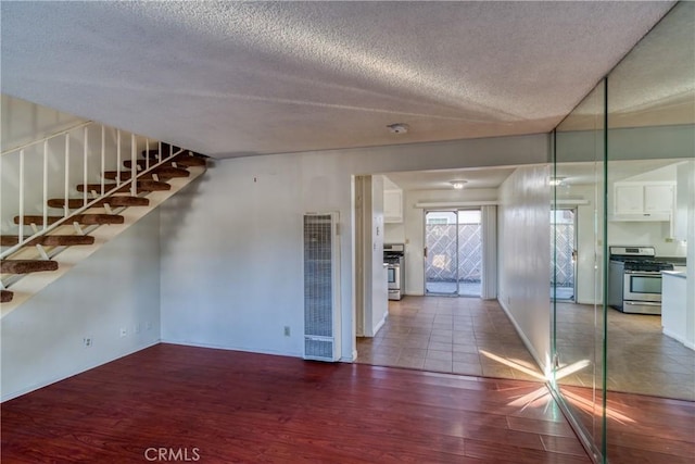 unfurnished room with stairway, wood finished floors, and a textured ceiling