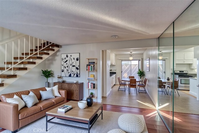 tiled living area with stairway, baseboards, and a textured ceiling