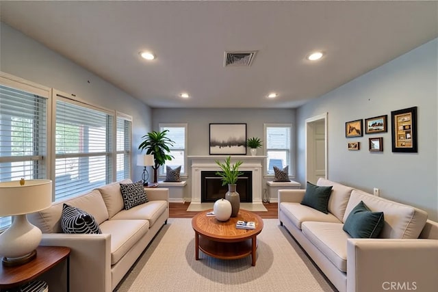 living room featuring plenty of natural light, wood finished floors, visible vents, and recessed lighting