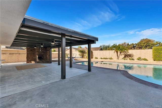 view of patio featuring a fenced in pool, ceiling fan, and an outdoor fireplace