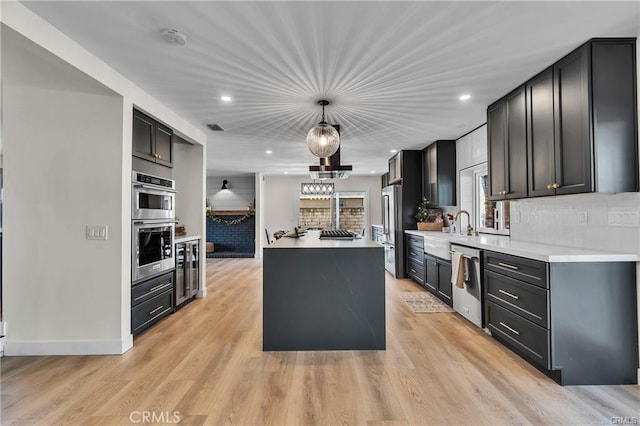 kitchen featuring pendant lighting, tasteful backsplash, appliances with stainless steel finishes, and light hardwood / wood-style flooring