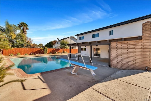 view of swimming pool with a patio area and a diving board