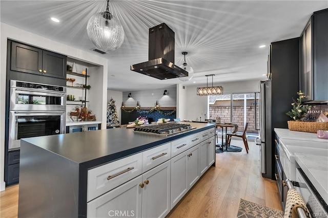 kitchen with hanging light fixtures, stainless steel appliances, light hardwood / wood-style floors, island range hood, and a kitchen island