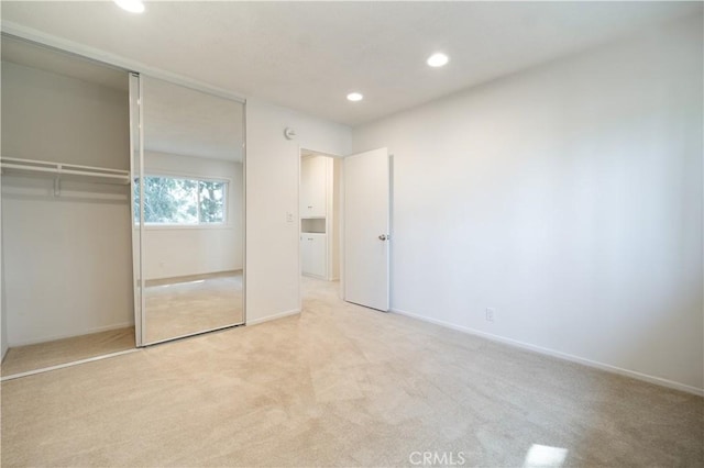 unfurnished bedroom featuring light carpet and a closet