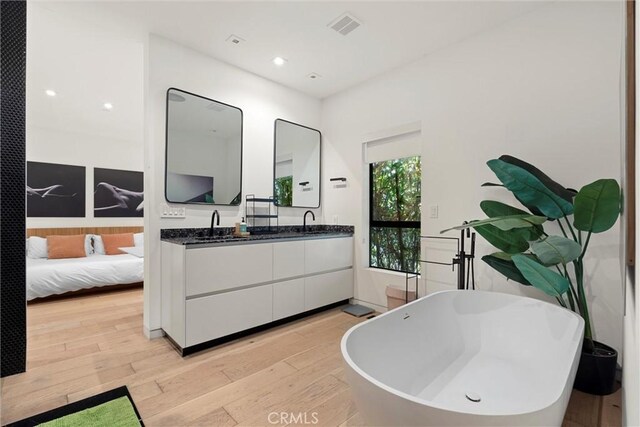 bathroom featuring hardwood / wood-style floors, vanity, and a bath