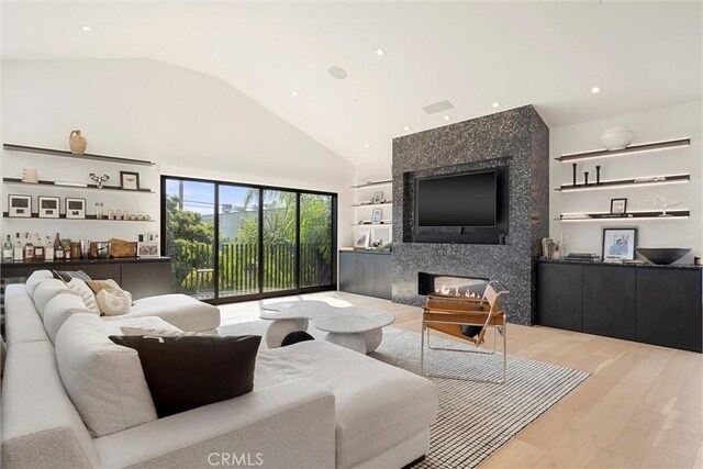 living room with lofted ceiling, light wood-type flooring, and a high end fireplace