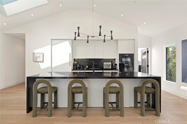 kitchen featuring white cabinets, a kitchen bar, light hardwood / wood-style floors, and sink