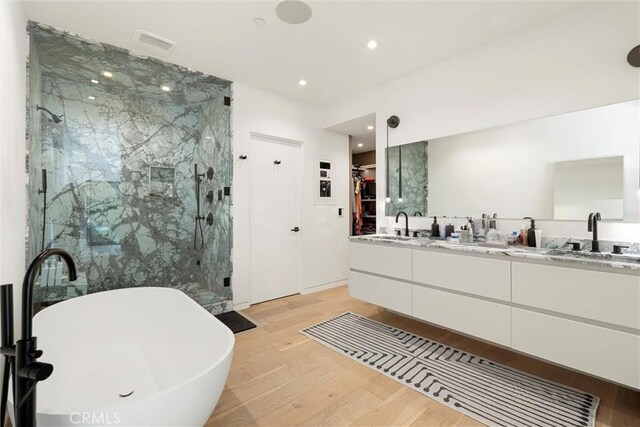 bathroom with hardwood / wood-style floors, vanity, and independent shower and bath