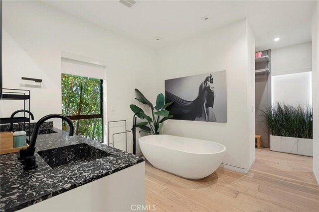 bathroom with hardwood / wood-style floors, vanity, and a washtub