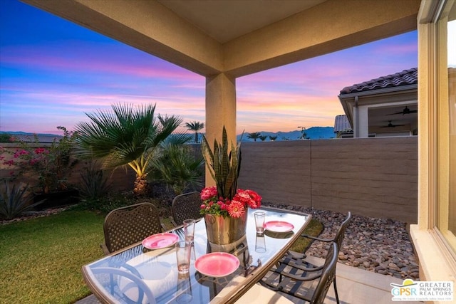 patio terrace at dusk featuring a yard