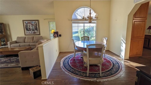 dining space with dark wood-type flooring and an inviting chandelier