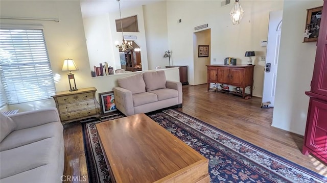 living room featuring a high ceiling, dark hardwood / wood-style flooring, and an inviting chandelier