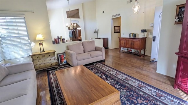 living room featuring a healthy amount of sunlight, dark wood-type flooring, and an inviting chandelier