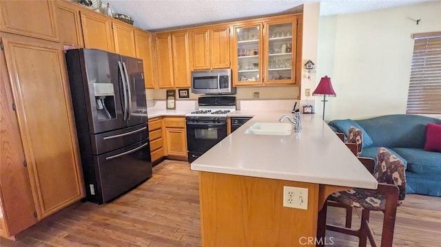 kitchen with kitchen peninsula, white gas range oven, sink, fridge with ice dispenser, and light hardwood / wood-style floors