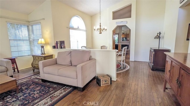 living room with a wealth of natural light, high vaulted ceiling, dark hardwood / wood-style floors, and an inviting chandelier