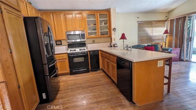 kitchen with sink, fridge with ice dispenser, black dishwasher, range with gas stovetop, and kitchen peninsula