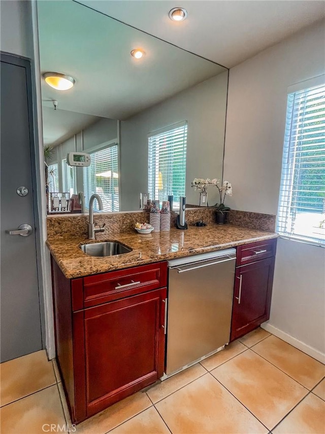 kitchen featuring dishwasher, sink, a wealth of natural light, and dark stone counters