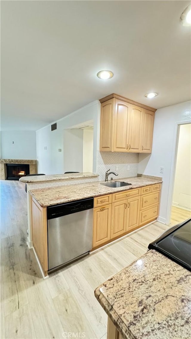 kitchen featuring sink, light brown cabinets, tasteful backsplash, stainless steel dishwasher, and light hardwood / wood-style floors