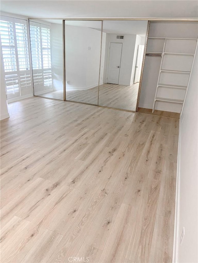 unfurnished bedroom with light wood-type flooring and a closet