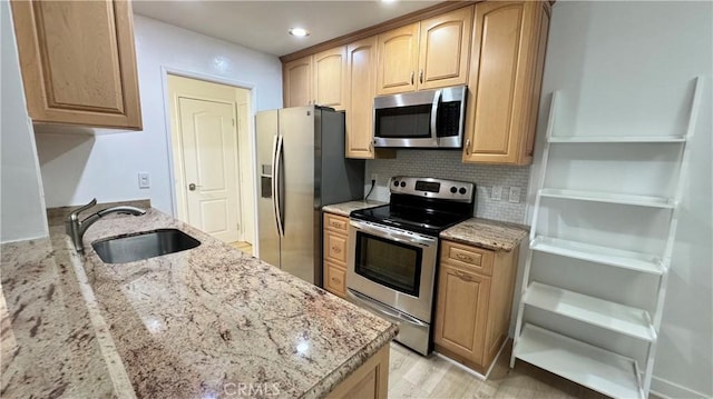 kitchen featuring decorative backsplash, sink, light stone countertops, and stainless steel appliances