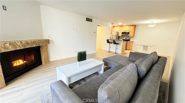 living room with light hardwood / wood-style floors and a premium fireplace