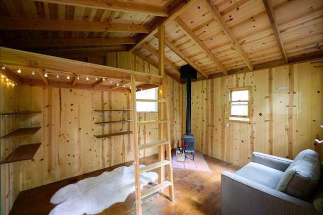 interior space featuring a wood stove, wooden ceiling, vaulted ceiling with beams, hardwood / wood-style floors, and wooden walls