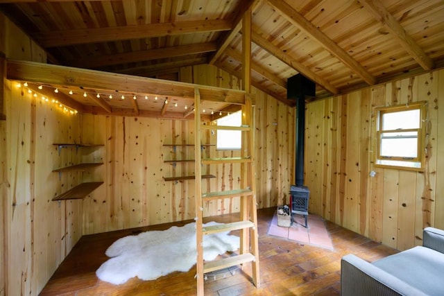 interior space with a wood stove, hardwood / wood-style flooring, multiple windows, and vaulted ceiling with beams