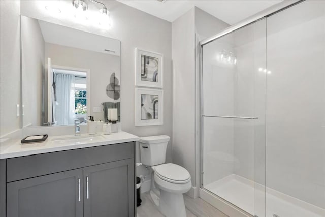 bathroom featuring vanity, a shower with shower door, and toilet