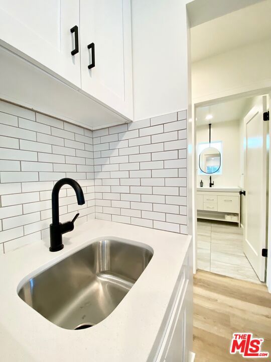 details with hardwood / wood-style floors, backsplash, and sink