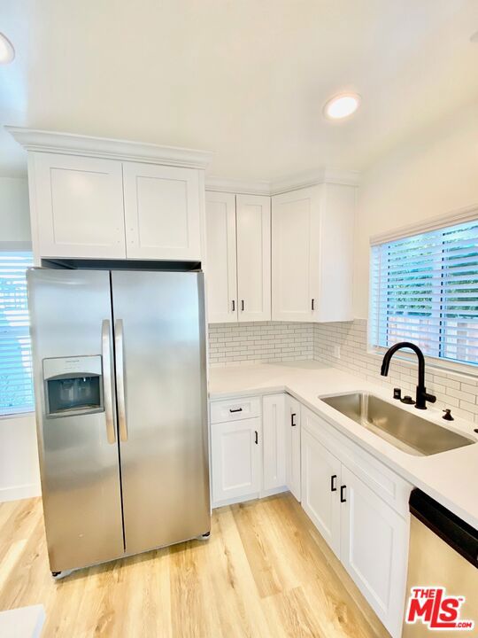 kitchen with decorative backsplash, sink, white cabinets, and appliances with stainless steel finishes