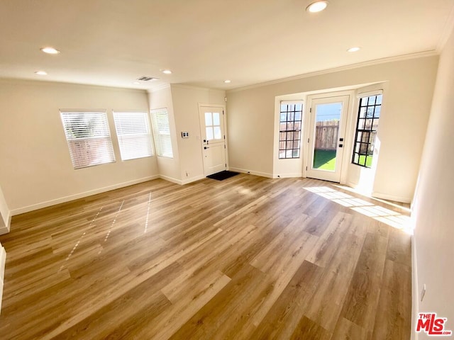 entryway with light hardwood / wood-style floors and crown molding